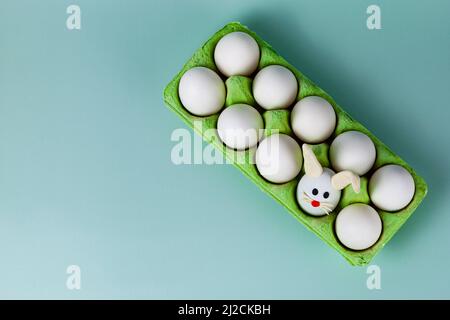 Happy Easter. Easter eggs. Chicken white eggs on green background. One egg with easter bunny ears. Closeup. Stock Photo