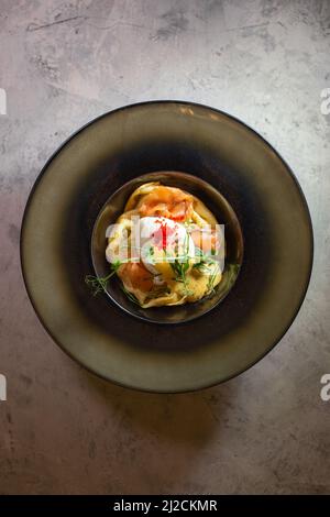 Pancake with salmon and cheese. Serving a dish in a plate on a gray background. Stock Photo