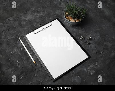 Blank letterhead, clipboard, pencil, succulent plant and clips on black plaster background. Responsive design template. Stock Photo