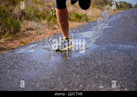 Cross country training. Cropped shot of a young man running on a country road. Stock Photo