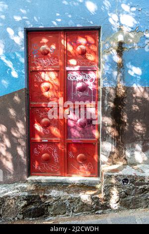 A door colored a bright red against a light blue building. San Miguel de Allende, Guanajuato, Mexico. Stock Photo