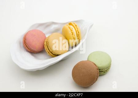 Closeup of a plate with some macaroons of different flavors (chocolate, pistachio, strawberry, lemon) on a white background Stock Photo