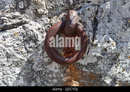 A rusty old metal ring attached to a limestone wall. Stock Photo