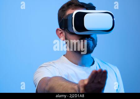 Young man using virtual reality headset and playing a game in metaverse with his friends. VR, future, gadgets, technology concept. Stock Photo