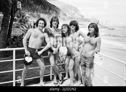 Australian rock group AC/DC takes time to relax at  Ipanema beach in Rio De Janeiro, Brazil during their visit to South America. They are in the city to perform at the  Rock In Rio Festival at the Rockedome, concluding their 'Flick Of The Switch' World tour.  Left to right: Singer Brian Johnson,  Cliff Williams, Simon Wright, Angus Young, Malcolm Young.  January 1985. Stock Photo