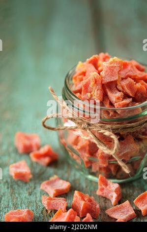 Homemade candied butternut squash pieces in glass jar and scattered on old painted table selective focus copyspace