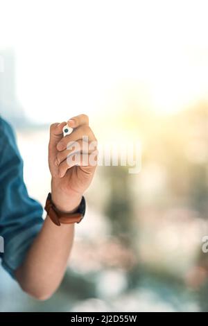 When in doubt, write it out. Shot of an unidentifiable young entrepreneur using a marker to write on a glass screen in the office. Stock Photo