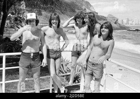 Australian rock group AC/DC takes time to relax at  Ipanema beach in Rio De Janeiro, Brazil during the visit to South America. They are in the city to  perform at the  Rock In Rio Festival at the Rockedome, concluding their 'Flick Of The Switch' World tour.  Left to right: Singer Brian Johnson,  Cliff Williams, Simon Wright, Angus Young, Malcolm Young.  January 1985. Stock Photo