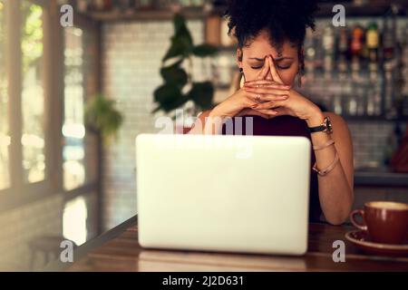 Some things just arent meant to work out. Cropped shot of a young woman looking stressed out while working on her laptop in a cafe. Stock Photo
