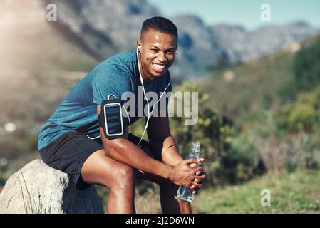 Resting for now before I get back to fitness. Cropped shot of handsome young male runner taking a break and drinking water outdoors. Stock Photo