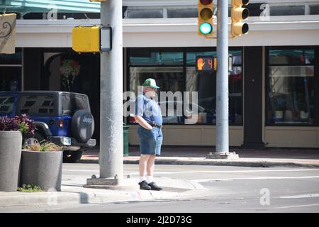 Elderly man wearing shorts and white socks stands on a street corner in Cheyenne Wyoming; August 2021 Stock Photo