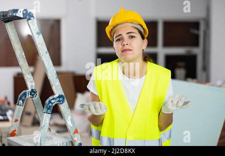 Sad woman builder standing in construction site Stock Photo