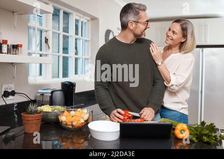 What are you cooking. Shot of a mature couple cooking together at home. Stock Photo