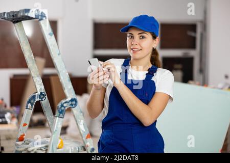 Female construction worker using smartphone in apartment Stock Photo
