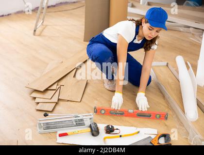 Young woman builder installing parquet Stock Photo