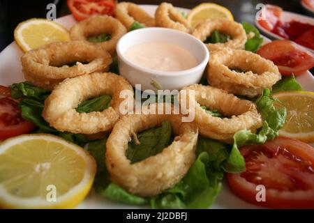 Squid rings with sauce on the dinner plate. Stock Photo