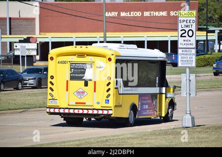 Small yellow Dallas Area Rapid Transit bus driving through a school zone - October 2021 Stock Photo