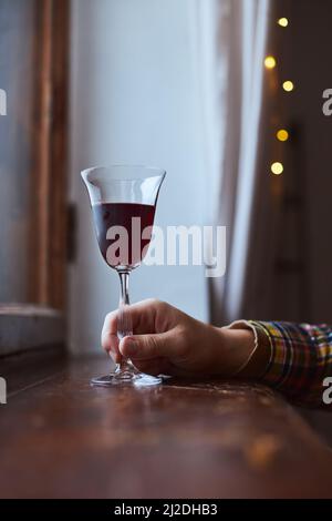 A young man drinks red wine from a vintage glass in an old mansion. Vertical photo. Stock Photo