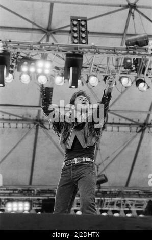 George Michael of Wham ! gets the crowd going at The Farewell Concert at Wembley Stadium, London on 28th June 1986. George Michael's real name is Georgios Kyriacos Panayiotou  Wham !,  (singer George Michael, and singer/guitarist Andrew Ridgeley) played their final concert as Wham !, although Andrew joined George as a guest on a few later George Michael solo shows.  Picture taken 28th June 1986 Stock Photo