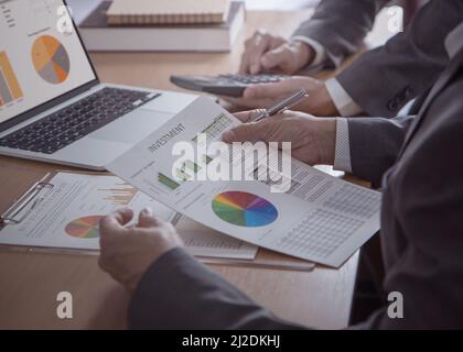 Two businessmen with laptop computer and calculator review financial statements for investment risk analysis and return on investment, ROI, in the off Stock Photo