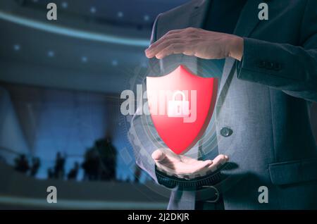 System administrator in gesture of expanding his hands holding a virtual red metal shield with padlock in system security and data protection concept Stock Photo