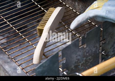Wooden wire brush for cleaning dirty barbecue grill. Leather protective glove. Stock Photo