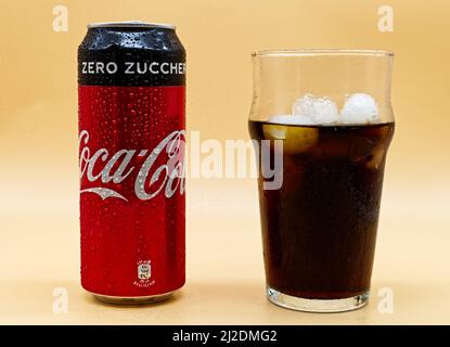 Bologna - Italy - November 17, 2020: Can of Coca Cola, glass and ice isolated on yellow background Stock Photo