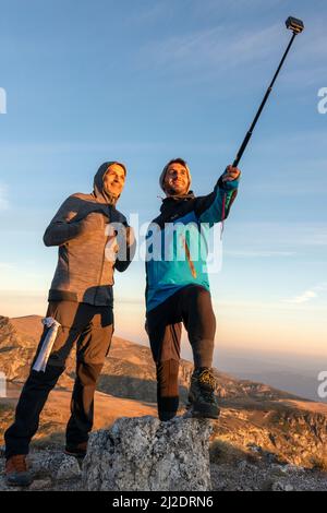 Male hikers taking selfie at the Seven Rila Lakes Circus in sunrise light, Rila Mountain, Bulgaria Stock Photo