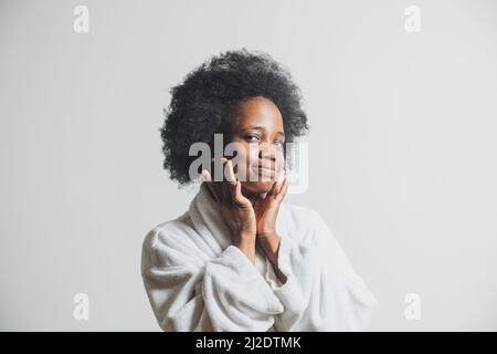 The happy woman is smearing her face with moisturizer Stock Photo