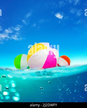 Inflatable balls float in water, split underwater sea image Stock Photo