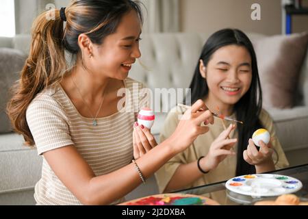 Happy family and Easter holiday concept, A beautiful asian woman enjoy prepare an Easter eggs with her younger sister. Easter egg painting. Stock Photo