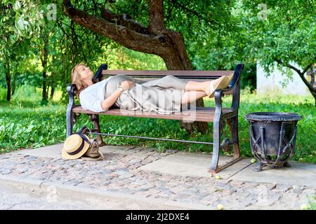 Pregnant woman lying on a park bench. High quality photo Stock Photo
