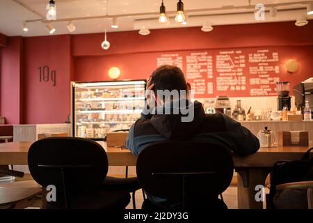 Worried busy man is sitting in cafe and working on complex project. Concept of ideas of lightbulbs over head. The chair is not comfortable, problems Stock Photo