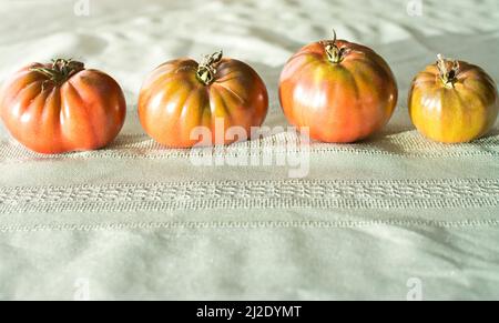 Four Black Krim heirloom tomatoes sitting on a table. Stock Photo