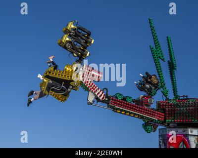 BIDEFORD, NORTH DEVON ENGLAND - MARCH 19 2022. Funfair ride, people upside down in the air. Blue sky. Stock Photo
