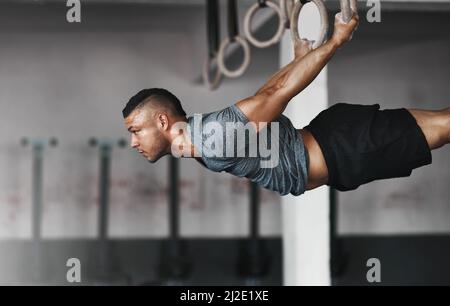 Pure power. Cropped shot of a young man working out on the gymnastics rings. Stock Photo