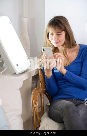 Woman smartphone light therapy Stock Photo