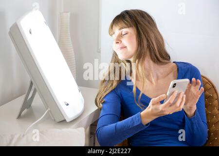 Woman smartphone light therapy Stock Photo