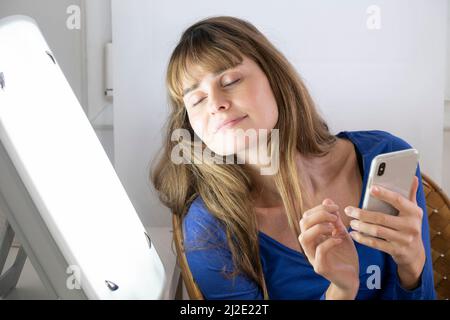 Woman smartphone light therapy Stock Photo