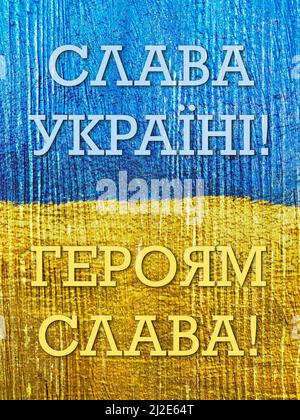 message Glory to Ukraine, Glory to Heroes in Ukrainian on flag painted on wooden wall Stock Photo