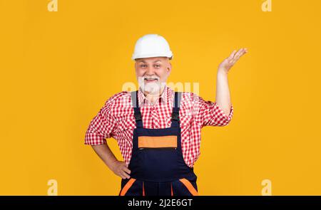 happy senior man builder in helmet on yellow background Stock Photo