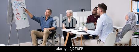Disabled Mature Businessman Giving Presentation To His Colleagues Stock Photo
