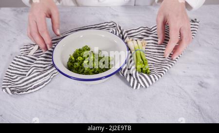 Step by step. Chopping organic green onions on a wood cutting board ...