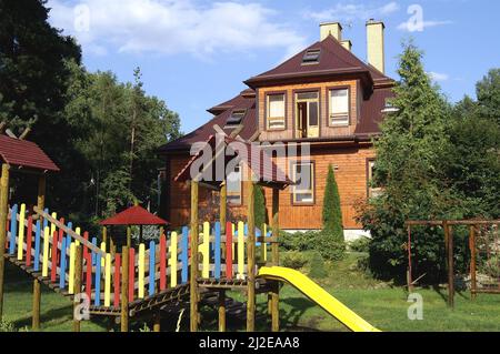 Augustów, Poland, Polen, Polska, Large wooden house surrounded by trees. Großes Holzhaus, umgeben von Bäumen. Duży drewniany dom otoczony drzewami. Stock Photo