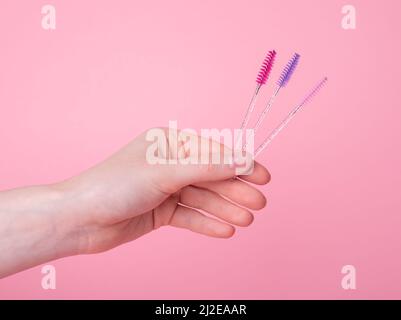Hand with disposable eyelash wands, brushes for separating lashes after applying mascara. Beauty, makeup, face care concept. Extension procedure. High quality photo Stock Photo