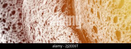 texture of slices white bread as close up background. gray backdrop of rough textured surface chopped pieces loaf of natural organic food with holes. Stock Photo