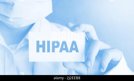 Doctor wearing face mask shows a card with the text HIPPA. Health Insurance Medical concept Stock Photo
