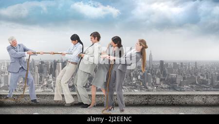 Composite image of businesspeople pulling on a rope during tug of war against view of cityscape Stock Photo