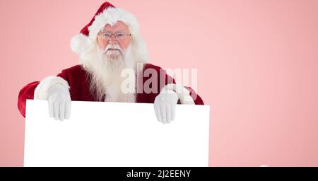 Portrait of santa claus holding a placard with copy space against pink background Stock Photo
