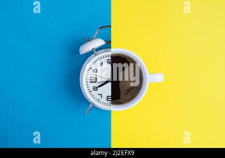 Collage of white alarm clock and coffee cup on the colored background. Top view. Copy space. Stock Photo
